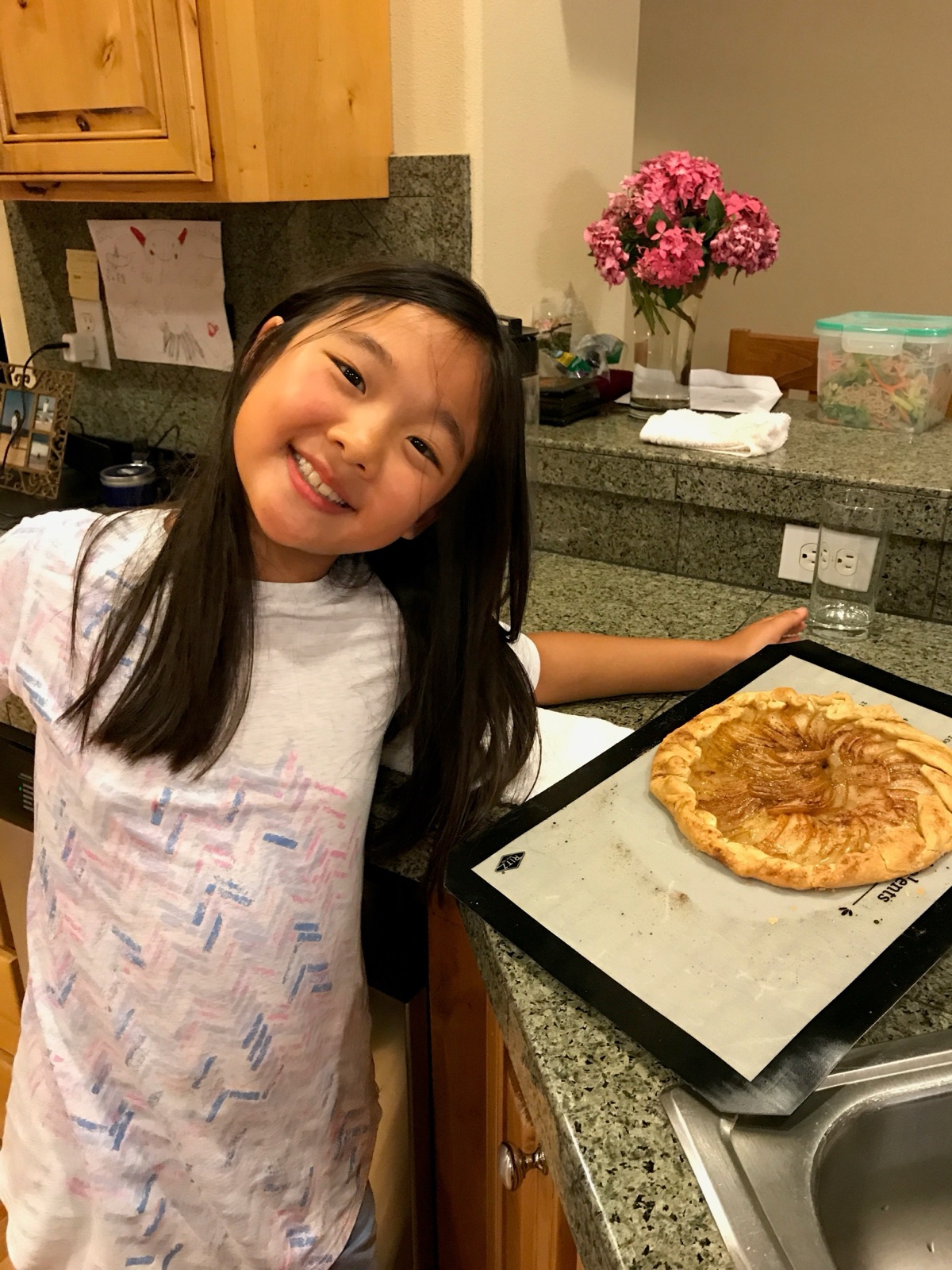 Marisa Woo smiling beside a homemade tart in the kitchen